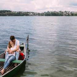 handsome guy and beautiful girl resting in a boat on the lake